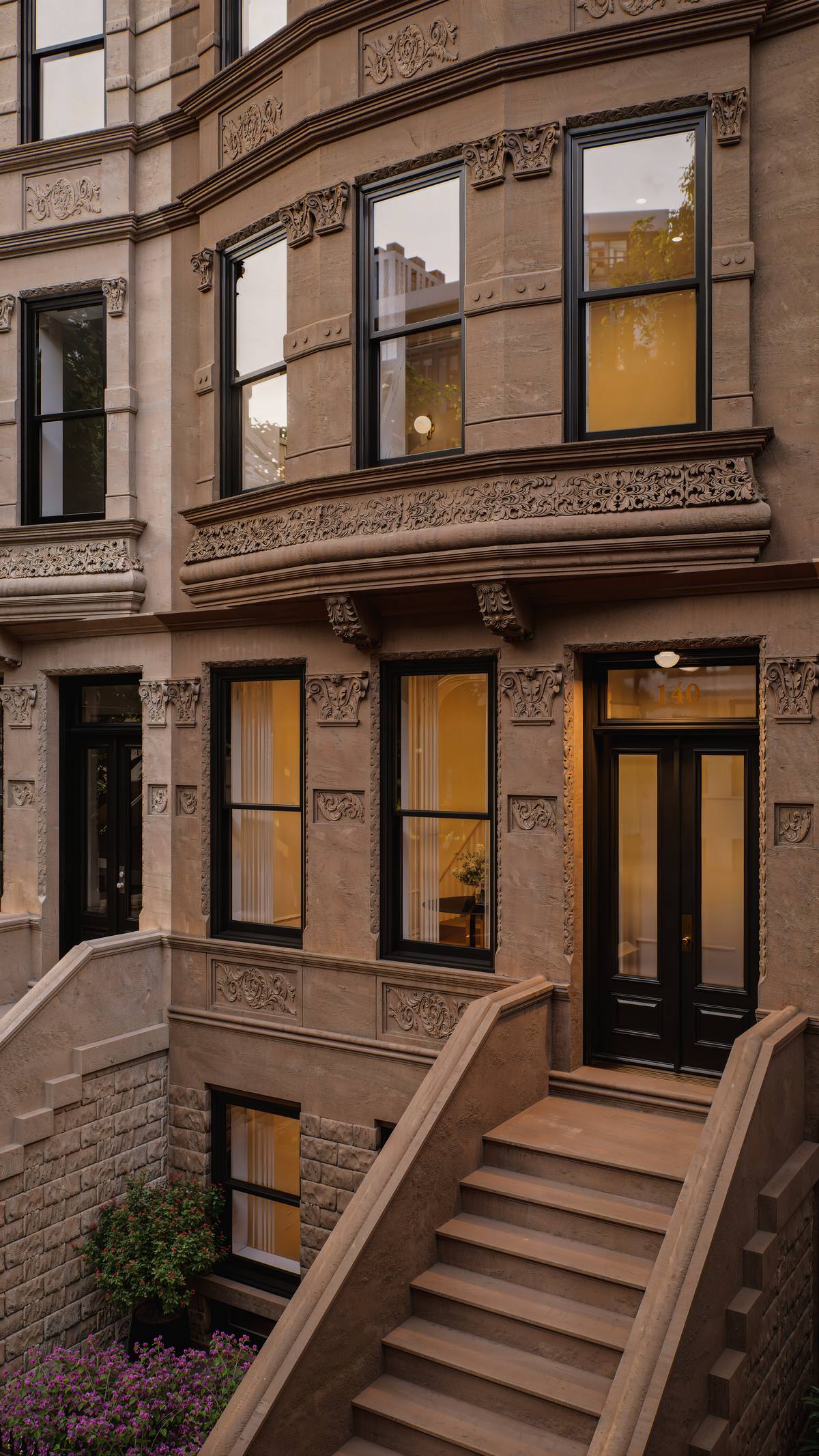 Parlor floor windows glowing at dusk